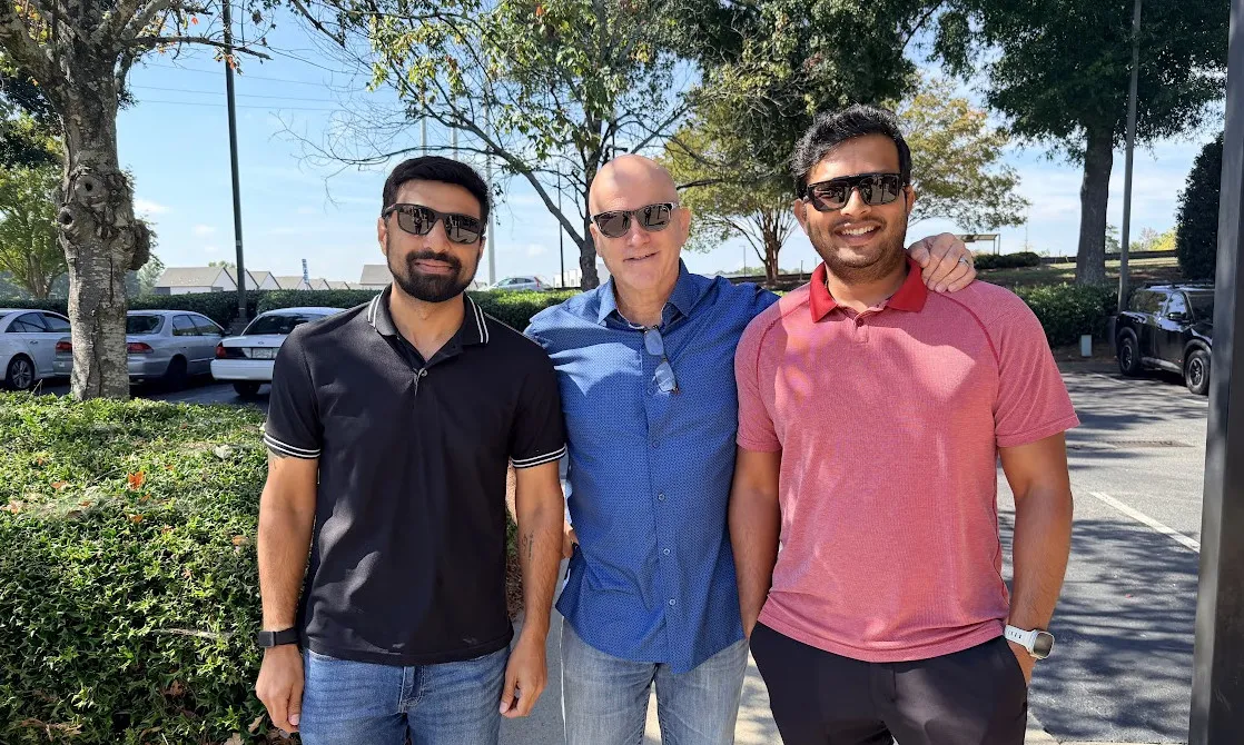 Three colleagues standing together outdoors on a sunny day