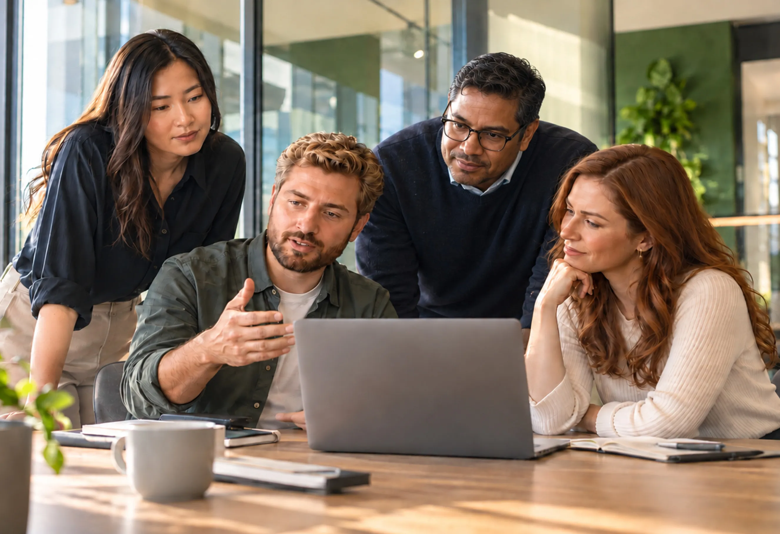 A team gathered around a laptop, talking through ideas in a bright office