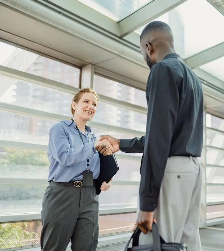 Two colleagues shaking hands in a bright corridor